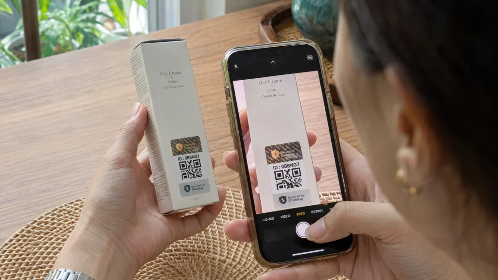 Konsumen mengarahkan kamera ponsel ke stiker Shieldtag pada kemasan kosmetik.